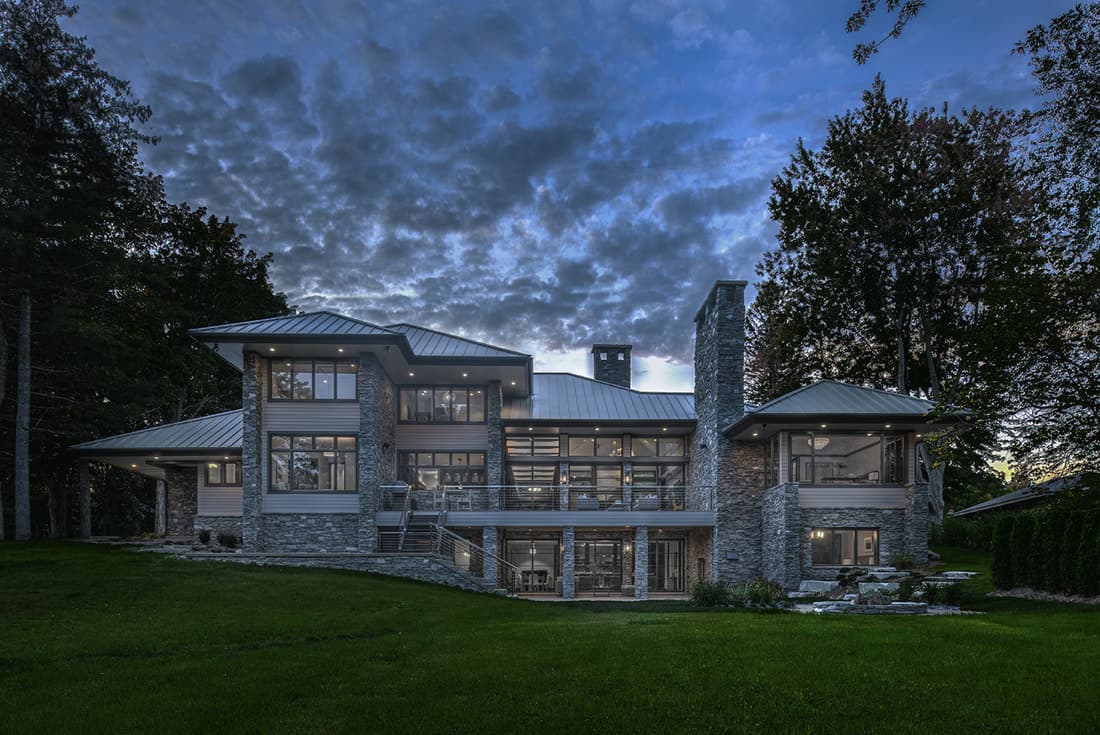 View of the house from the backyard showcasing its massive windows and spacious porches.