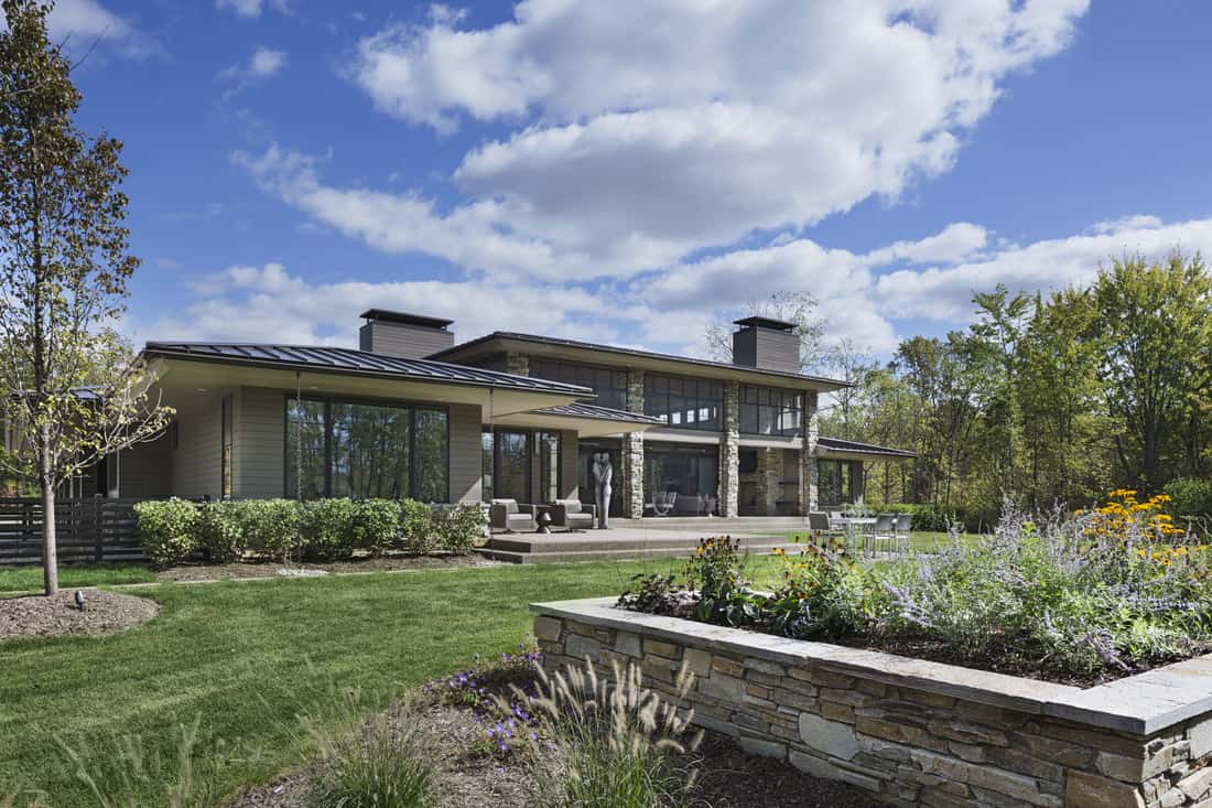 The outdoor living is complemented by a lush lawn and lovely plants.