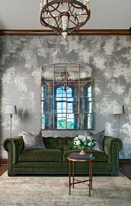 Distressed concrete wall and framed mirror add rustic touches to the living area.