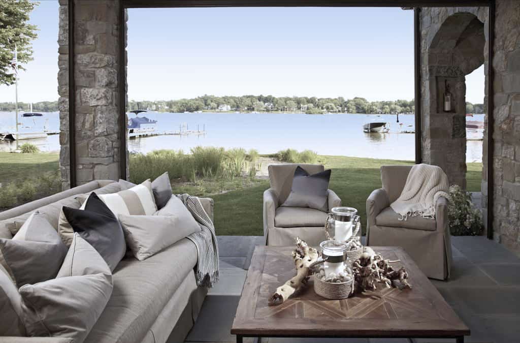 Outdoor living with skirted seats and a wood-top table over the stone-tiled floor.