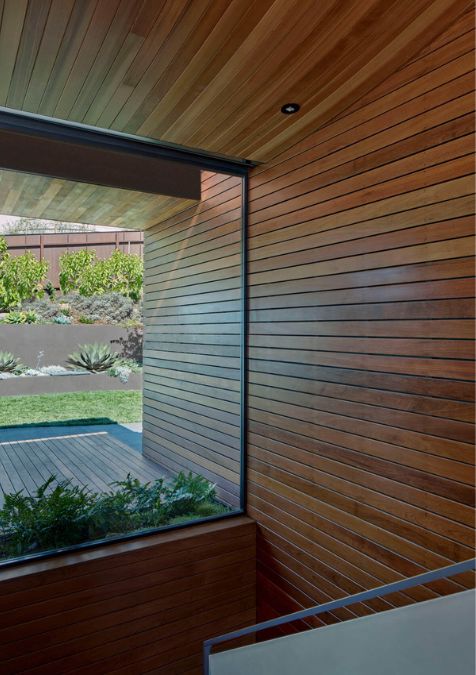 The image offers a glimpse of the exterior garden space, visible through a glass wall from the viewpoint of the staircase.