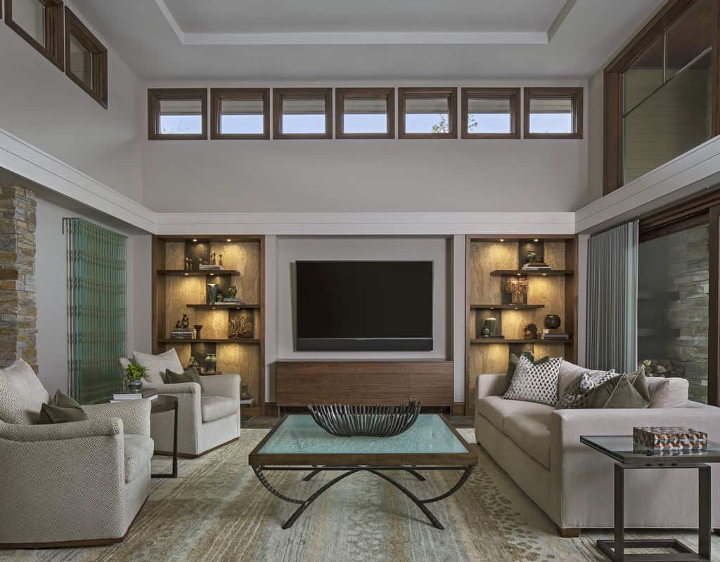 The living room has gray seats and a wall-mounted TV flanked by floating shelves.