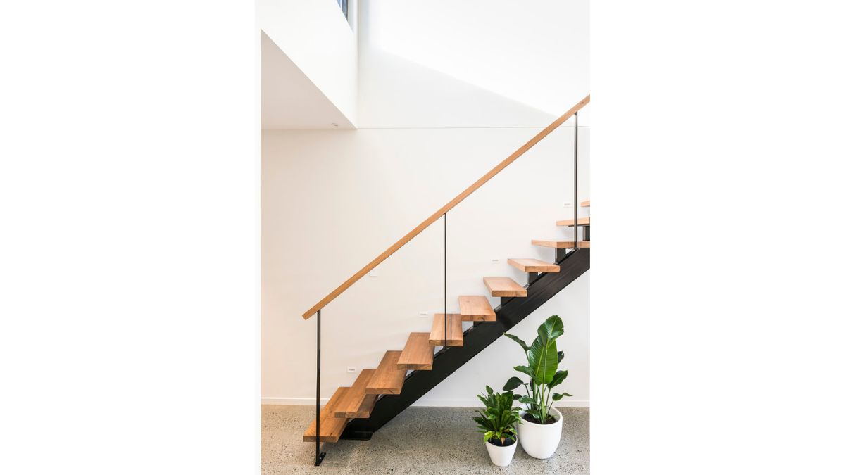 A stairway with a glass rail leads to the second floor.