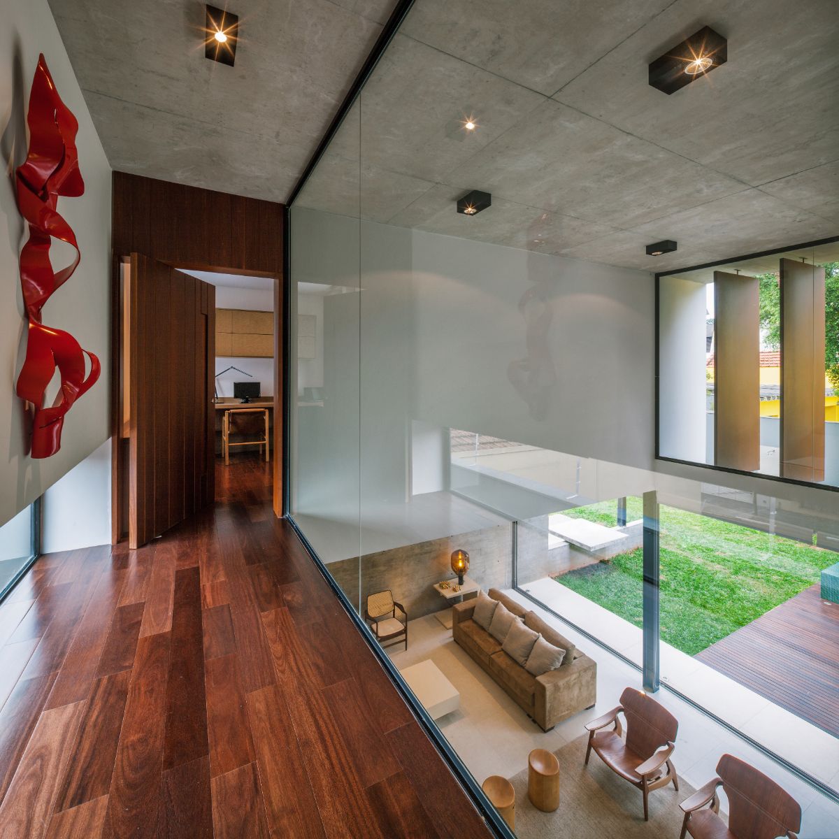 The hallway to the bedroom has wood flooring and glass walls.