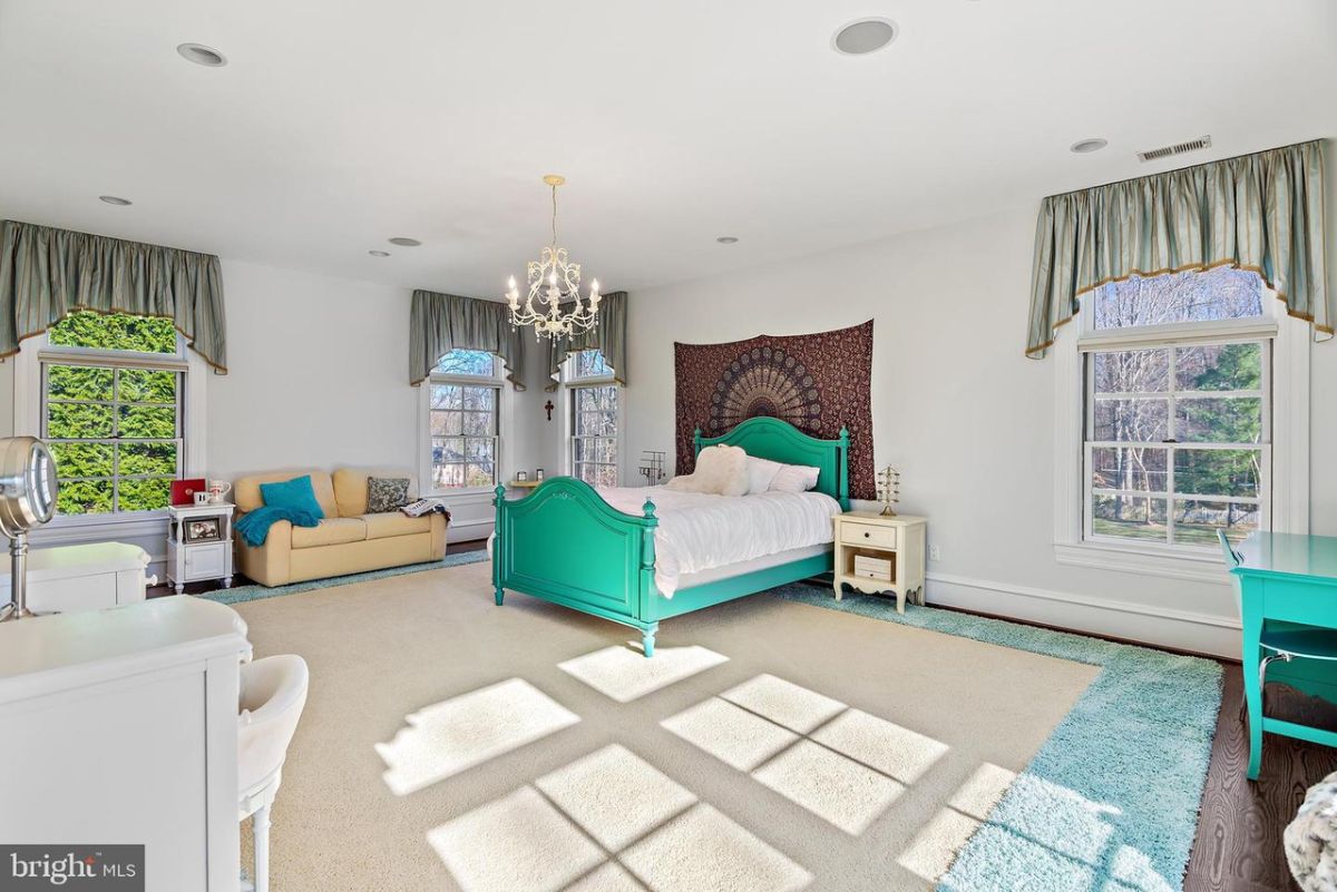 The bedroom is decorated with chandeliers and an area rug giving the room a cozy feel.