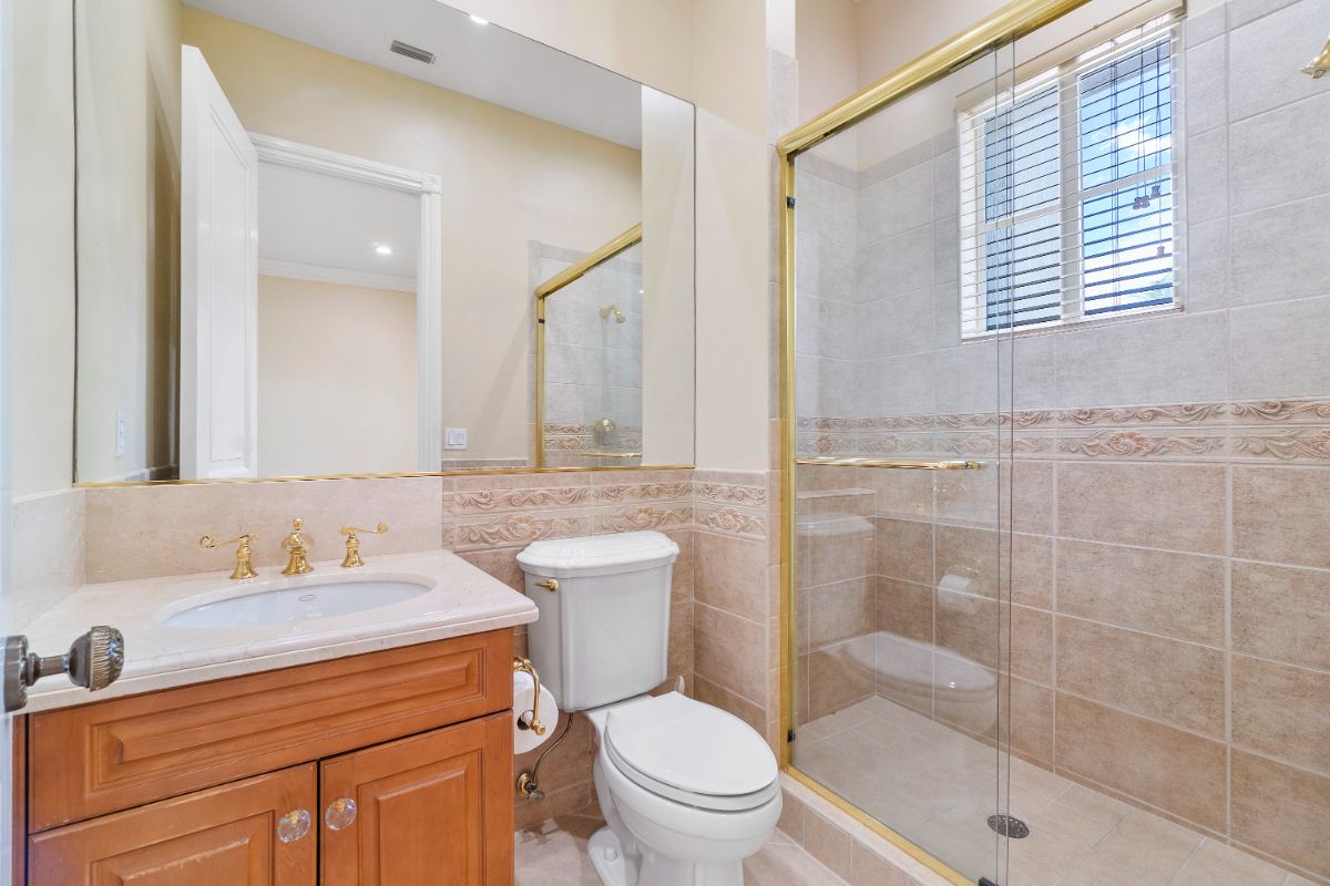 The bathroom features a shower cubicle and a vanity with gold-plated fixtures.