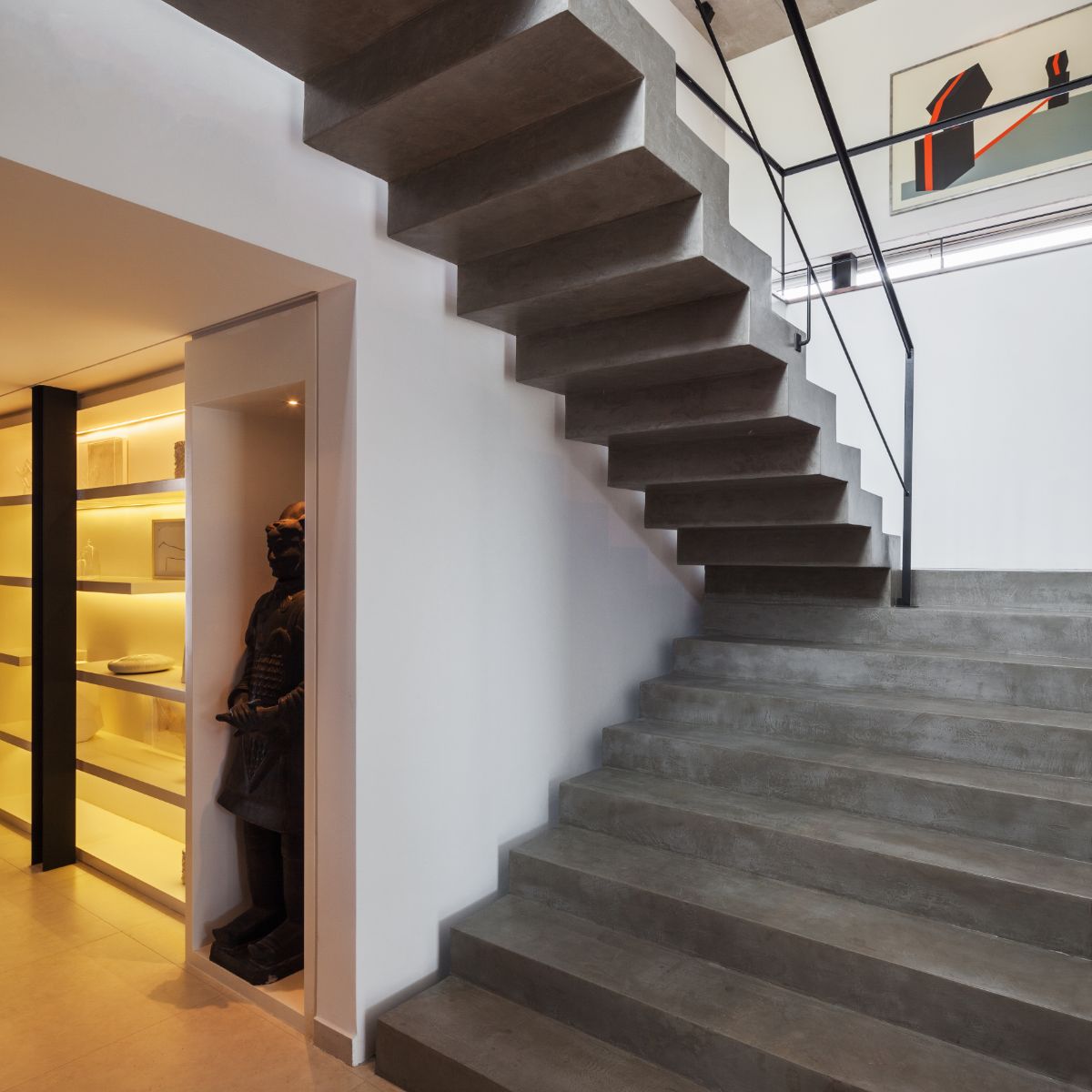 The staircase inside the house is made of exposed concrete and decorated with artwork.