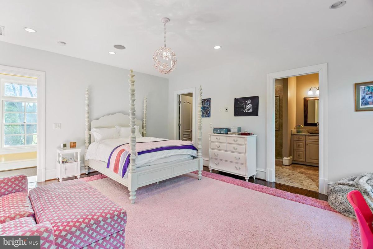 The bedroom is decorated with chandeliers and a pink carpet, giving the room a feminine feel.