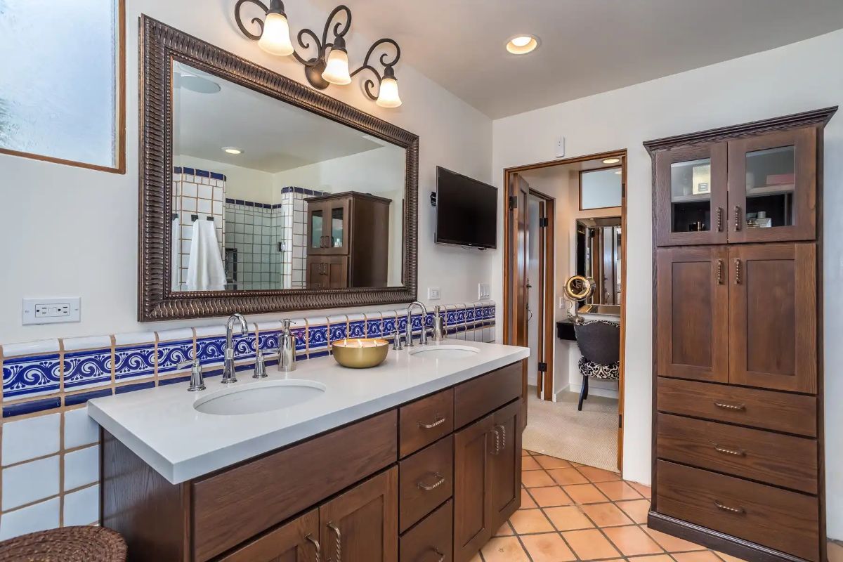 The bathroom features a vanity with a tile countertop and wooden drawers.