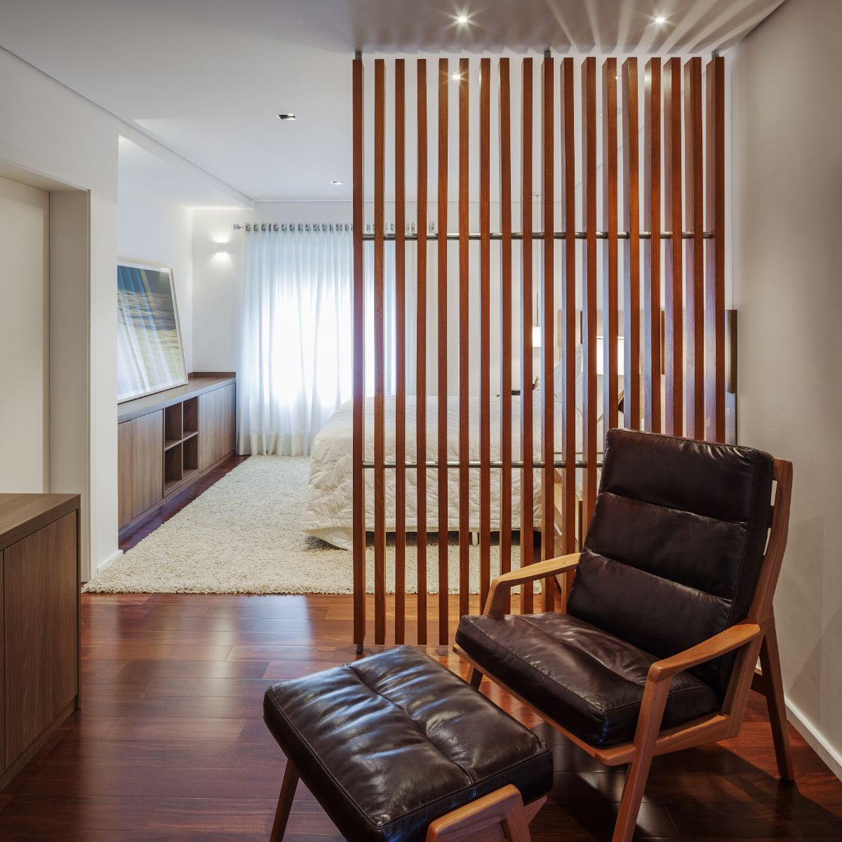 The bedroom features a chaise and an area rug giving the place a cozy atmosphere.