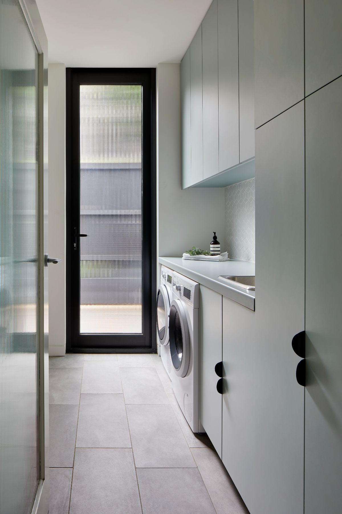 Laundry in a renovated 1930’s house in Melbourne. Features slate gray wide Fog tile from Glux and obscure glass door, with reeded glass from Viridian as a nod to the art deco heritage of the house.