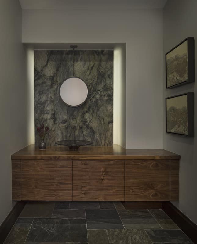 This powder room features a floating vanity with a vessel sink and a marble backsplash.