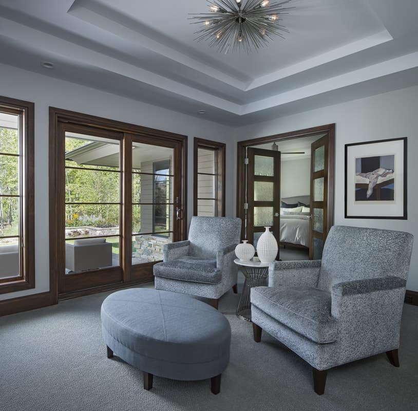 Sitting room with a step ceiling and gray armchairs that blend in with the carpeted floor.