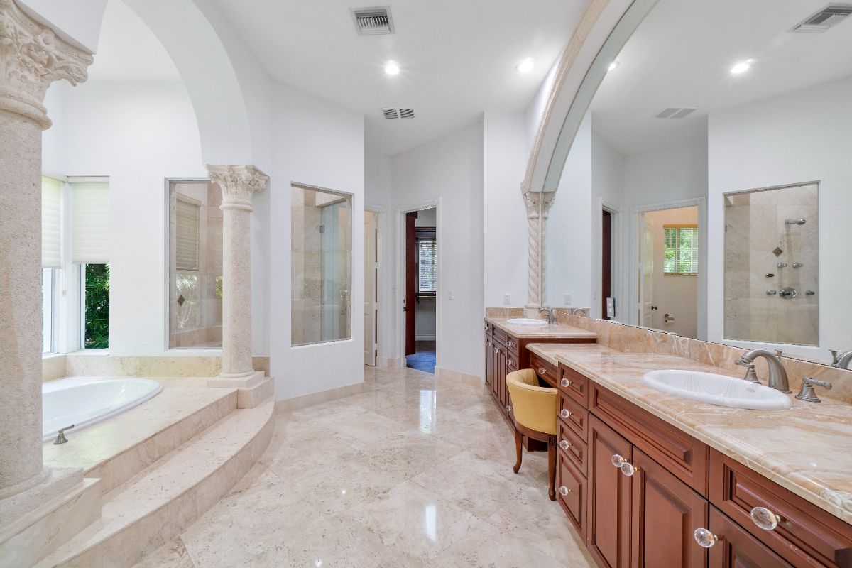 The master bathroom features a built-in bathtub, and the presence of Corinthian columns gives the room a classic feel.