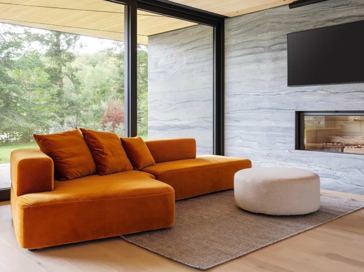 A vibrant orange couch brings a pop of color to this living space.