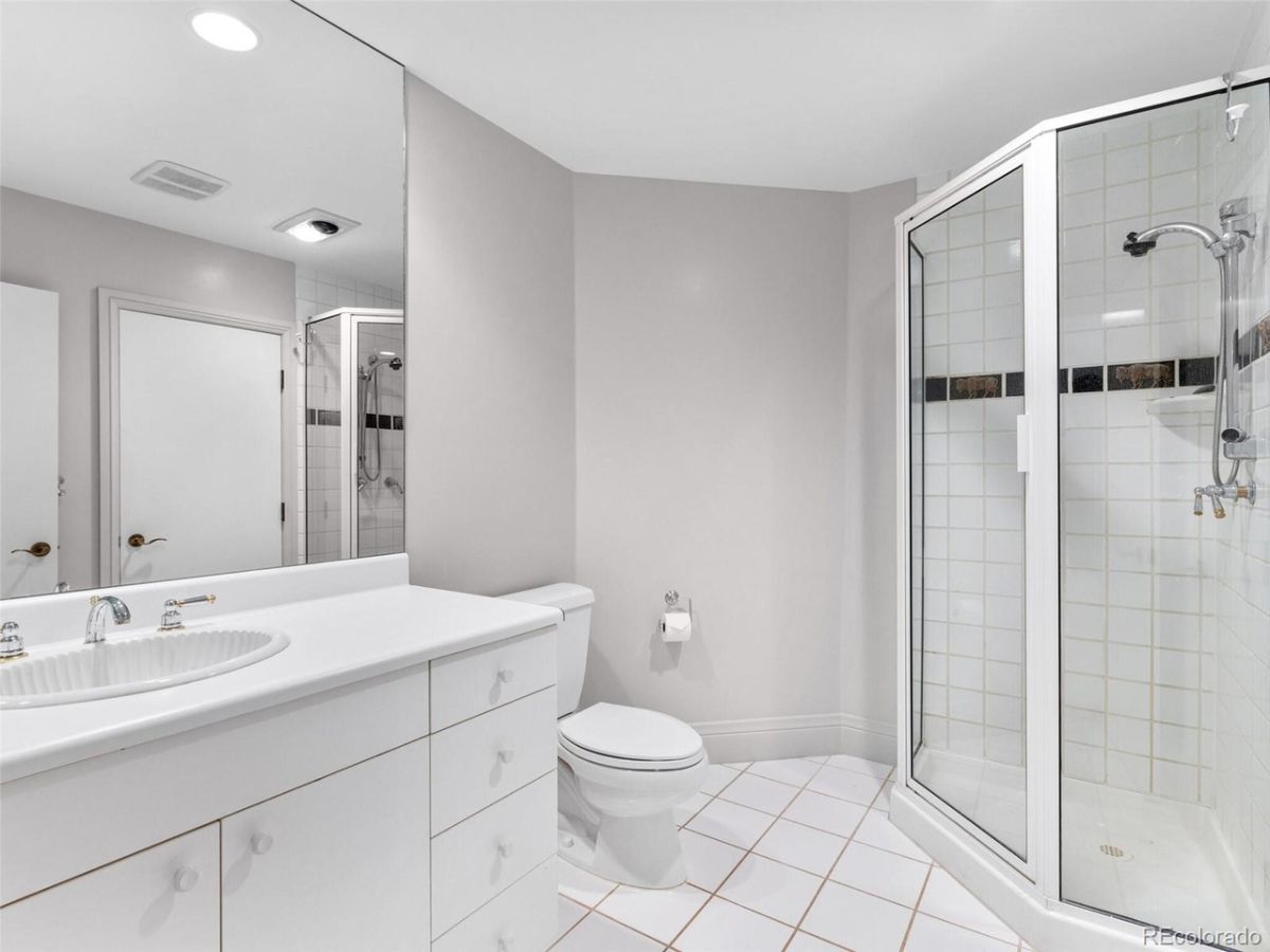 A white themed bathroom featuring a shower cubicle and a vanity.