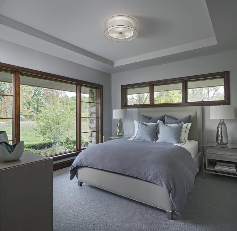 This bedroom has a tray ceiling and large windows that look out the garden.