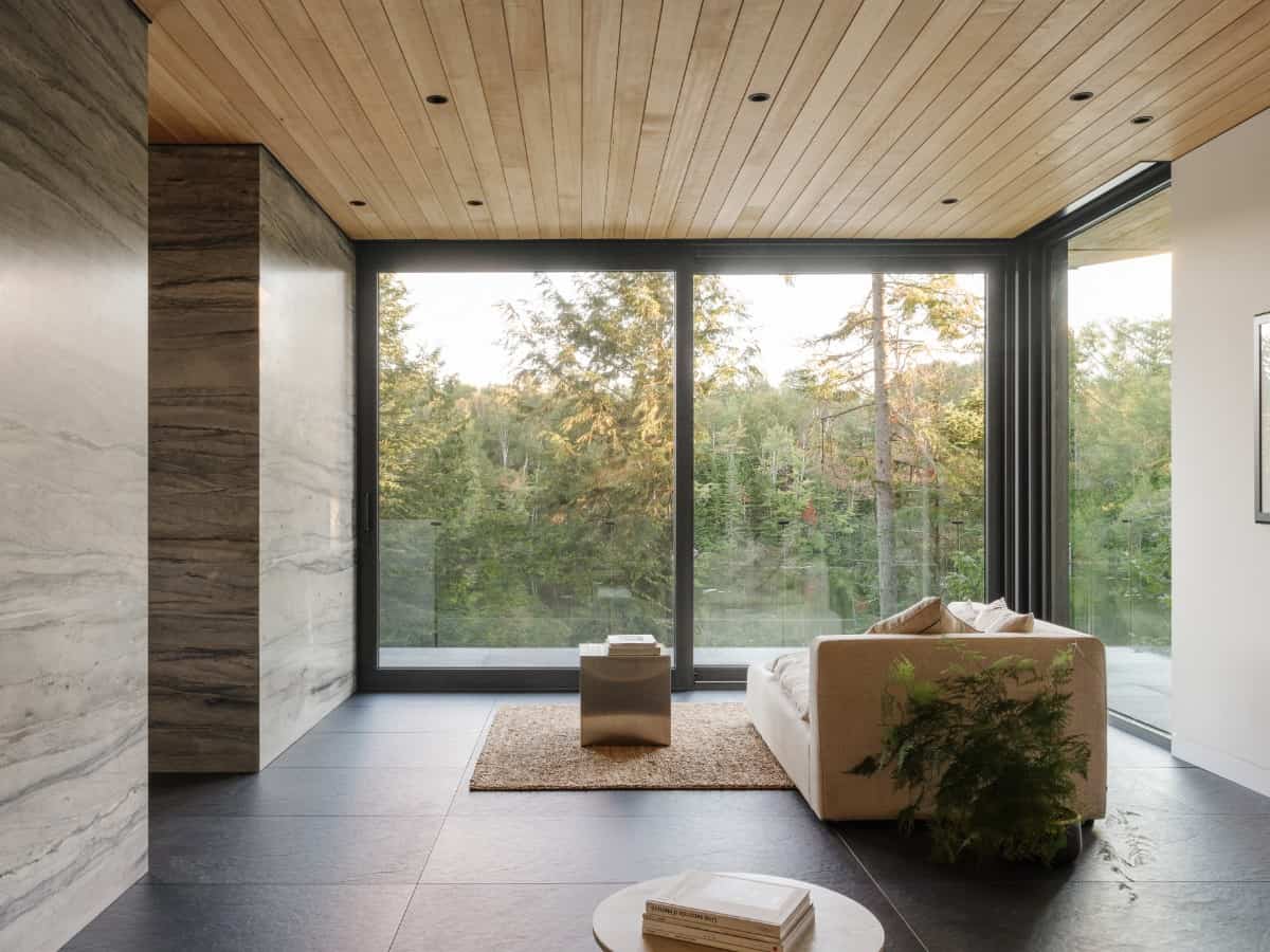 This living area's relaxing vibe is enhanced by the surrounding forest that can be seen through the oversized glass sliders.