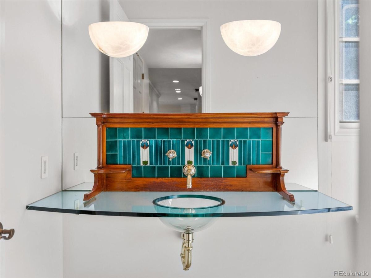 The house features a sink with a glass counter, and the fixtures give a luxurious feel to the room.