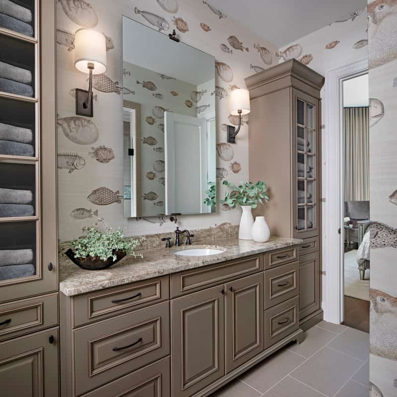 The fish wallpaper sets a nice backdrop to this brown vanity flanked by tall cabinets. 