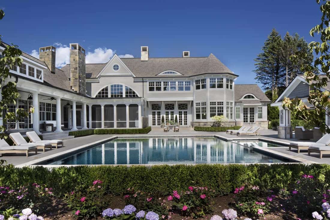 A view of the house from the backyard showcasing its screened and covered porches along with a pool cabana.