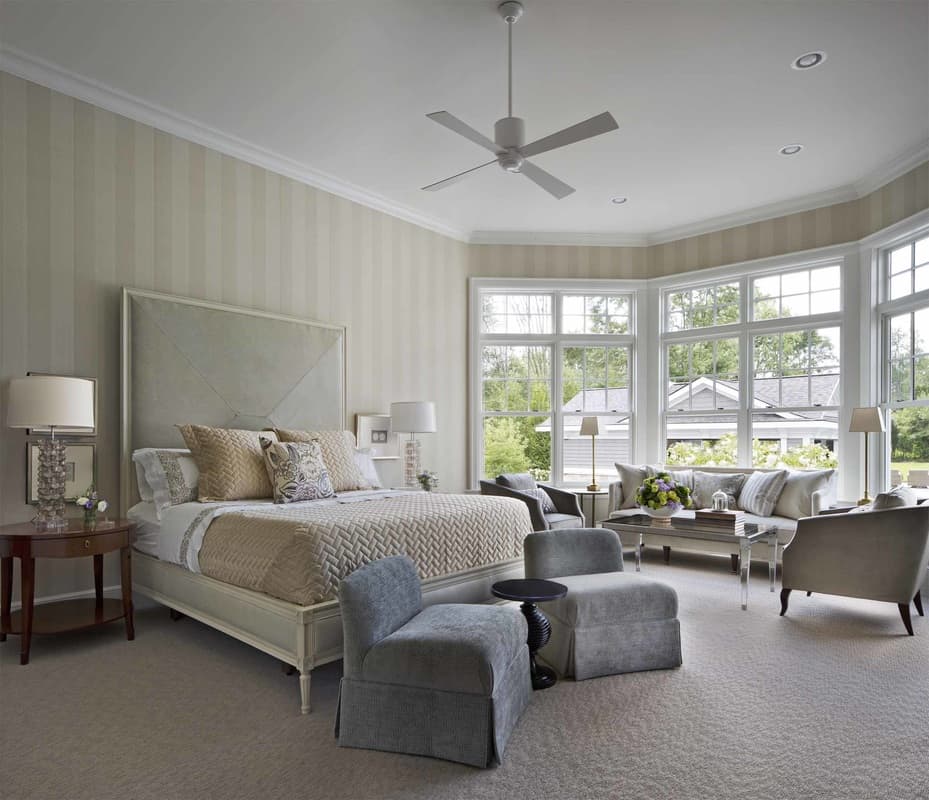 The primary bedroom has carpeted floor and a sitting area by the bay window.