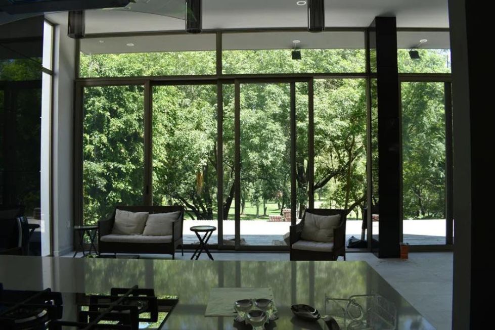 This photograph, taken from the kitchen, showcases the seamless integration between the living area and the outdoor space through the use of an expansive glass wall and door.