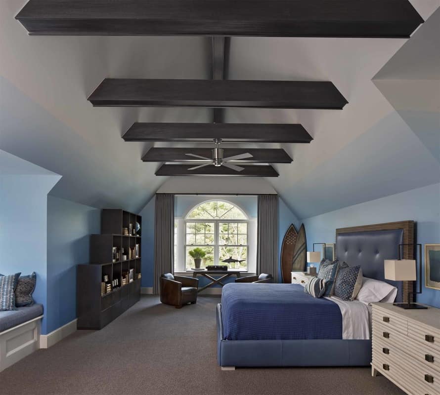 A vaulted ceiling lined with dark wood beams tops this blue bedroom.