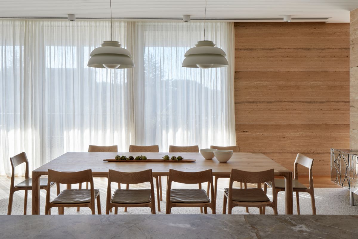 The dining area features a chandelier and glass walls with curtains to regulate sunlight.