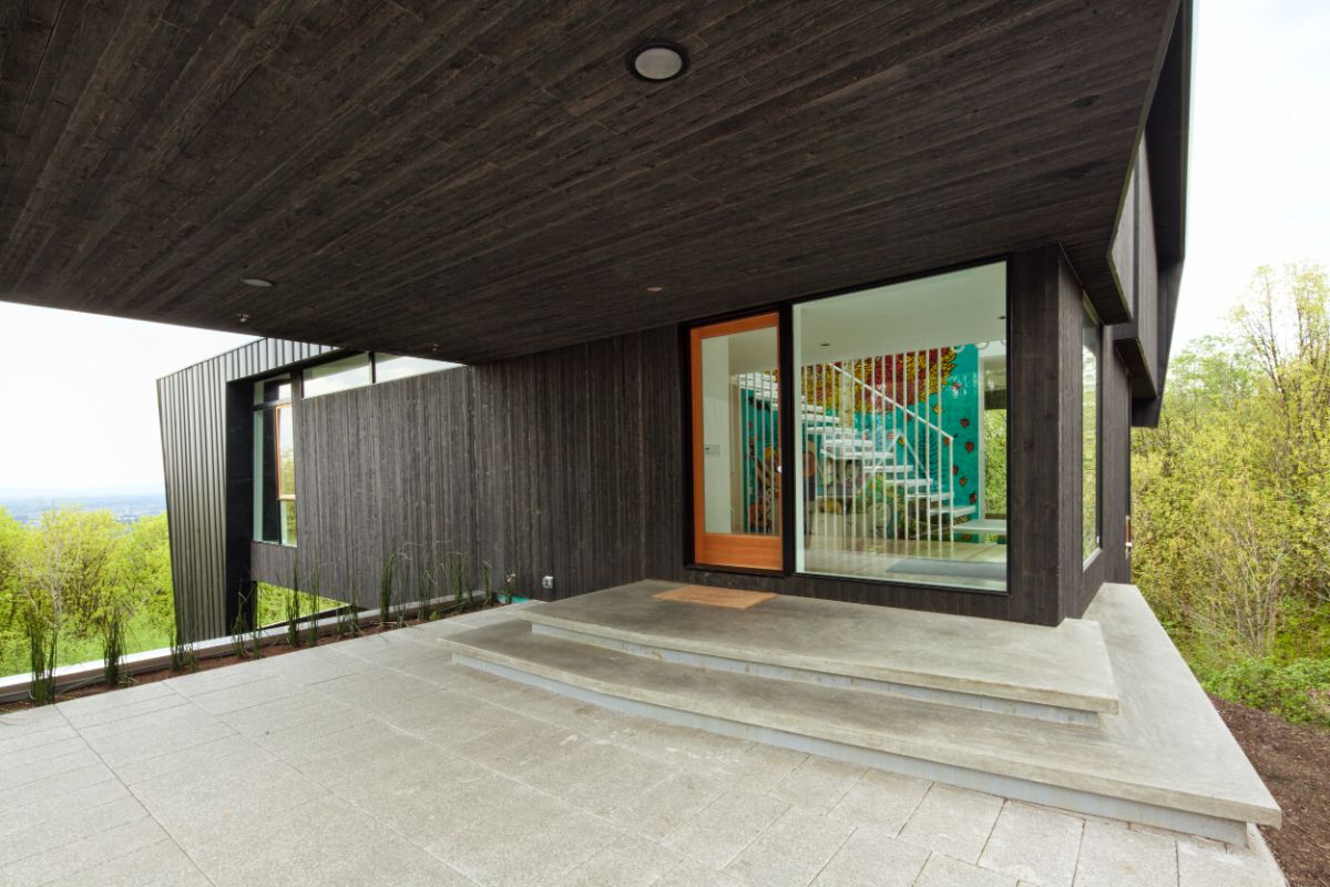 Large concrete slab steps lead the visitor up from the sidewalk under the bedroom module to a generous front porch.