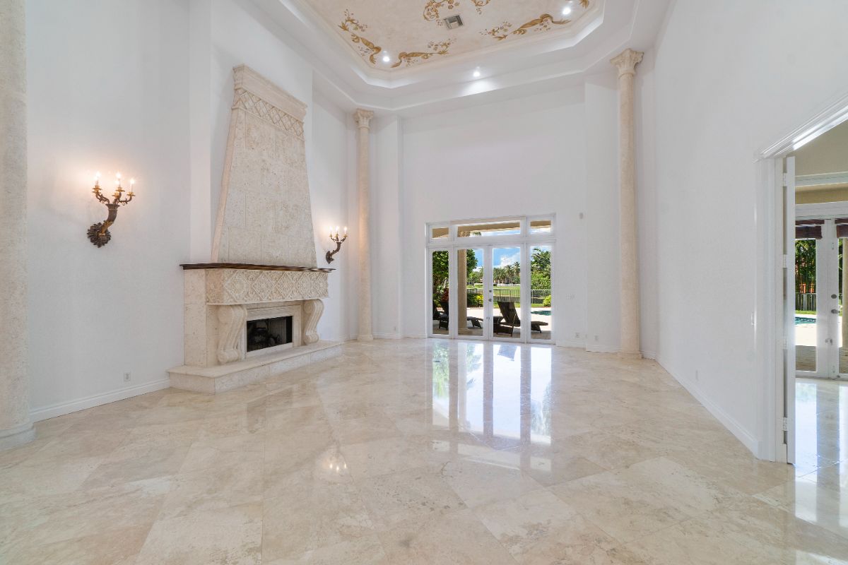 The living area features a fireplace and ceiling artwork. The Corinthian columns give the house a classic feel.