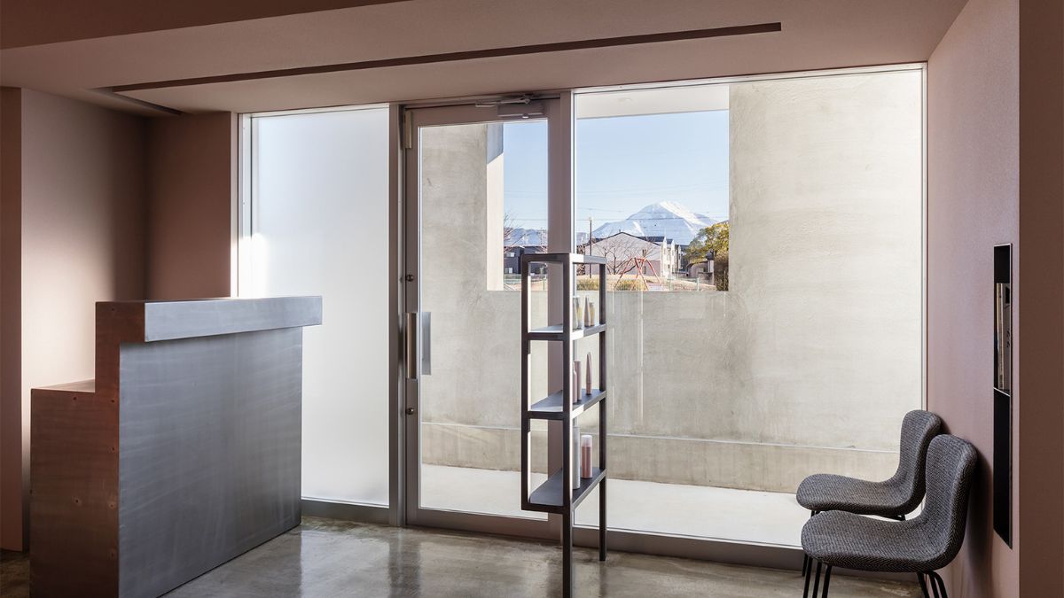 A glass door and the front desk for the hair shop are located at the home's entryway.