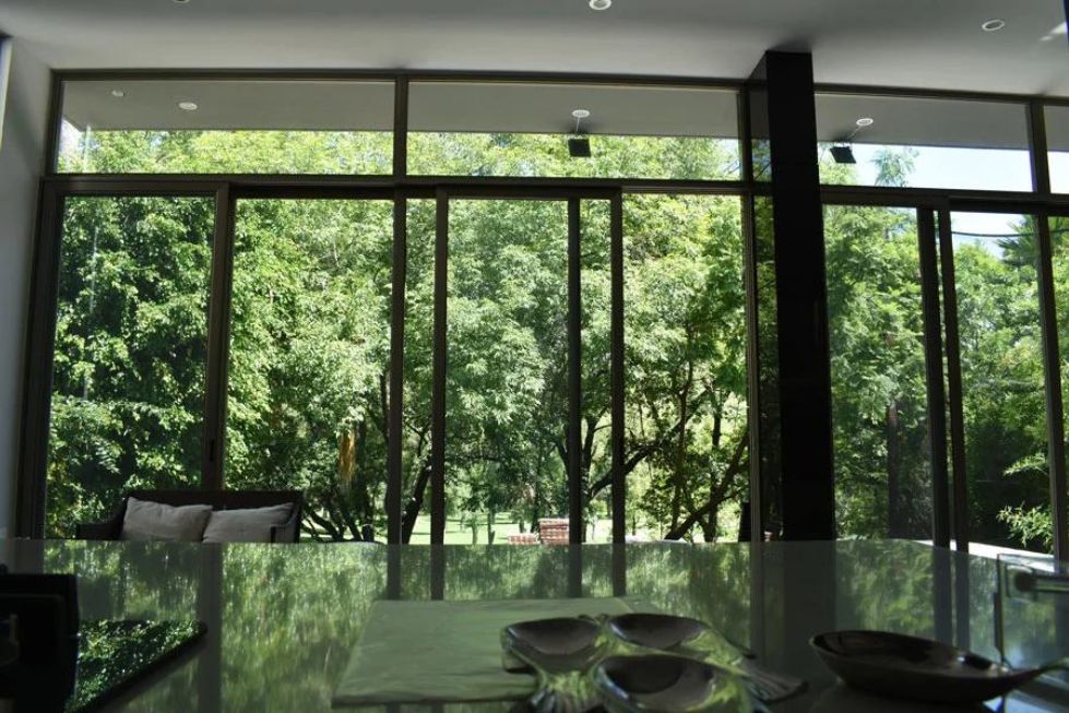 This is an interior photograph taken inside a spacious living room, with a focus on the massive glass wall panels that provide a view of the outdoors.