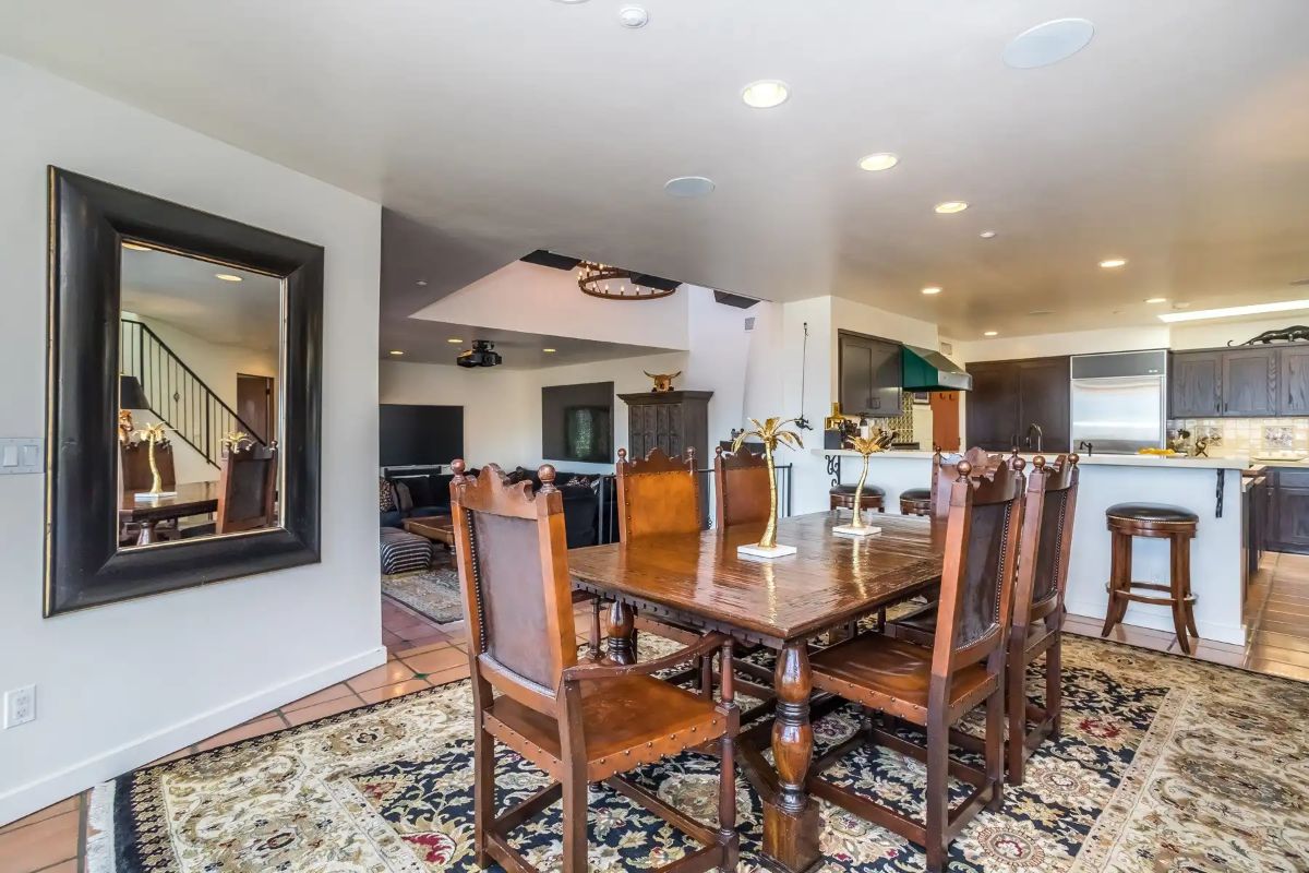 The dining area features a wooden table that blends well with the carpet giving off a rustic feel.