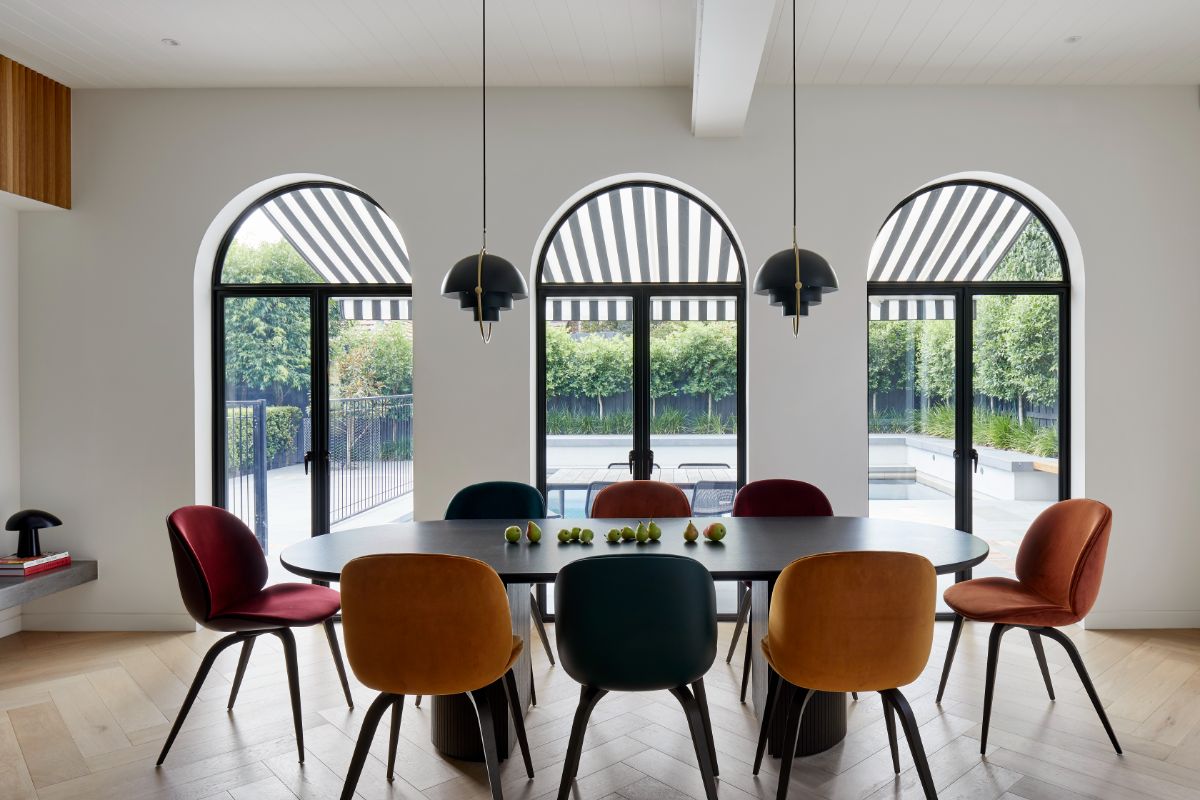 The dining room features unique chandeliers, and the glass doors showcase the view of the swimming pool.