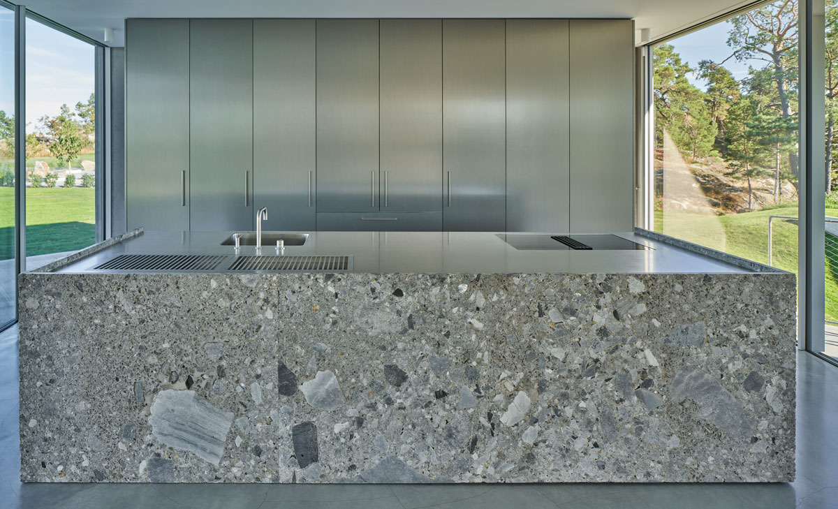 The kitchen features a kitchen peninsula made of marble tile and large glass walls to light the place during the day.