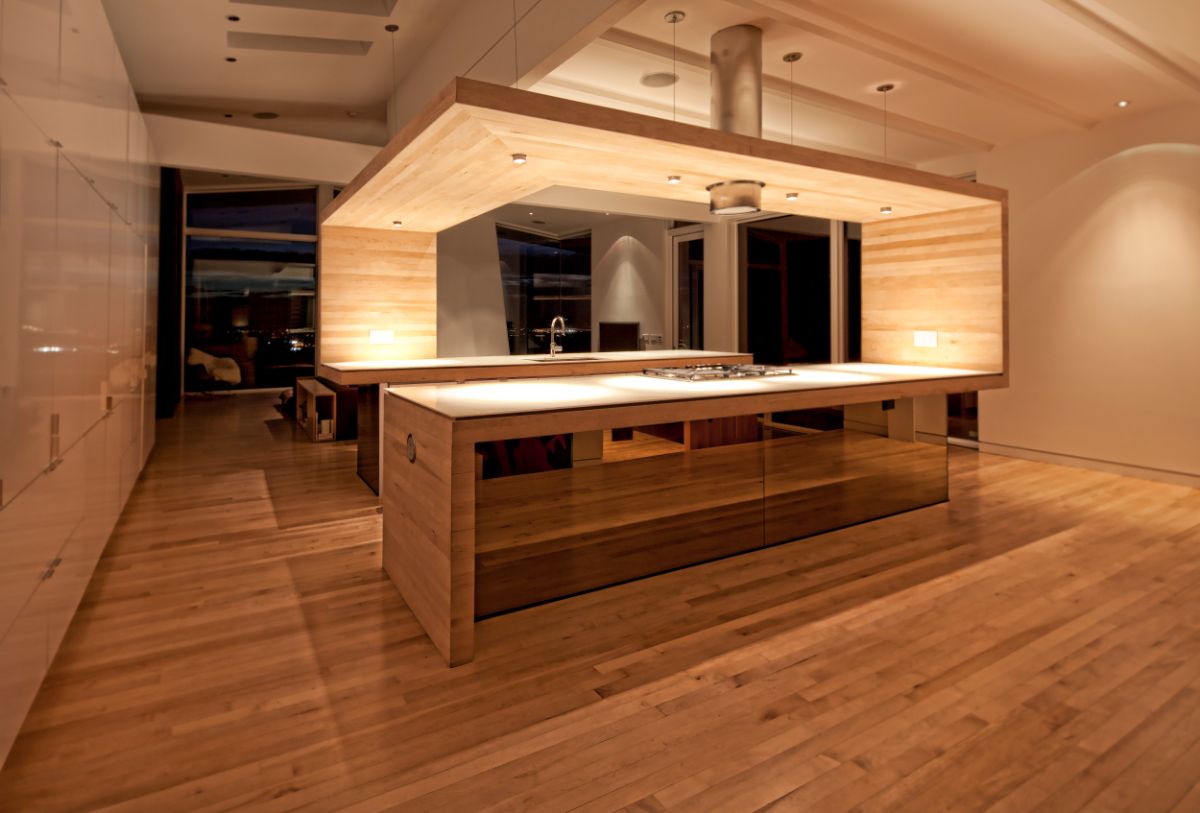 The kitchen, a figure clad in reclaimed maple flooring and bronze mirror, defines the middle of this space and is the centerpiece of the home.