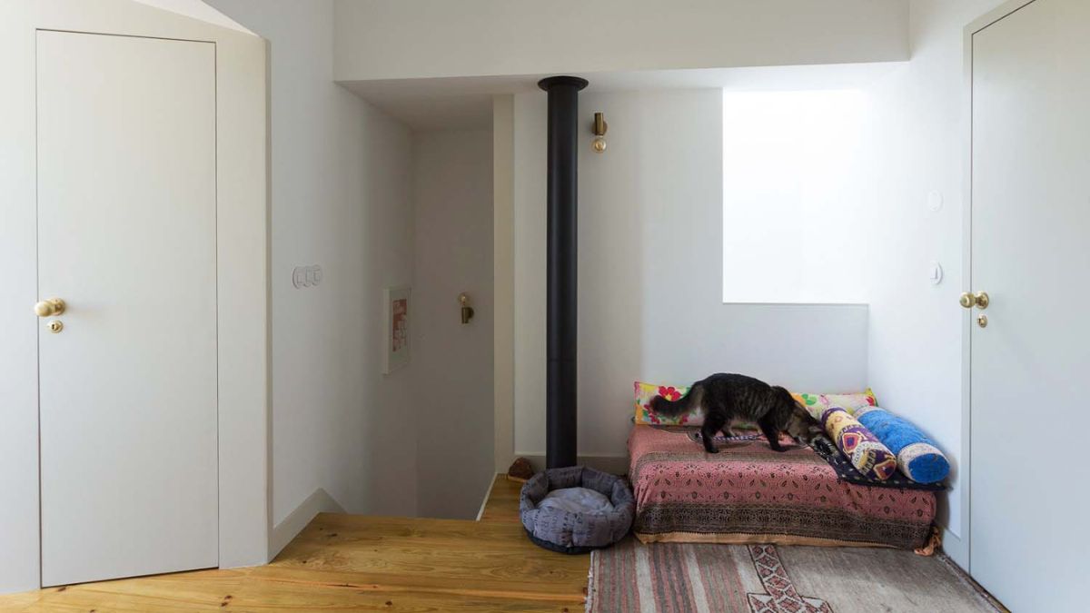 The upper portion of the house includes wooden floors and walls painted entirely in white.