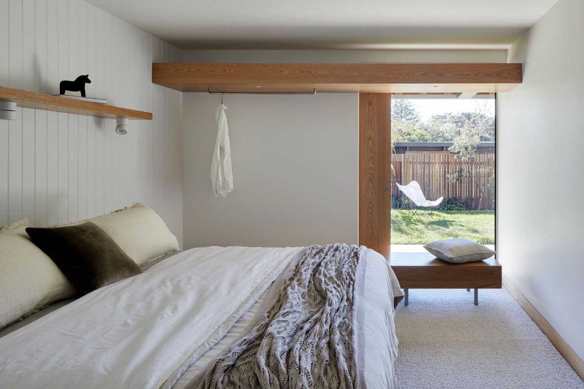 The bedroom features a bedroom bench with a glass wall that regulates sunlight and offers a view of the backyard.