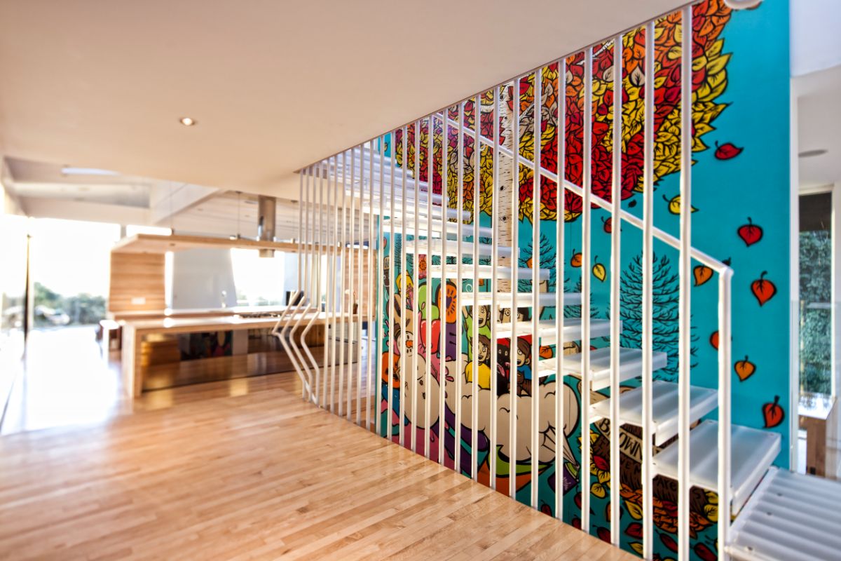 The staircase with etched acrylic stair treads and a light steel framework is lit with a skylight during the day.