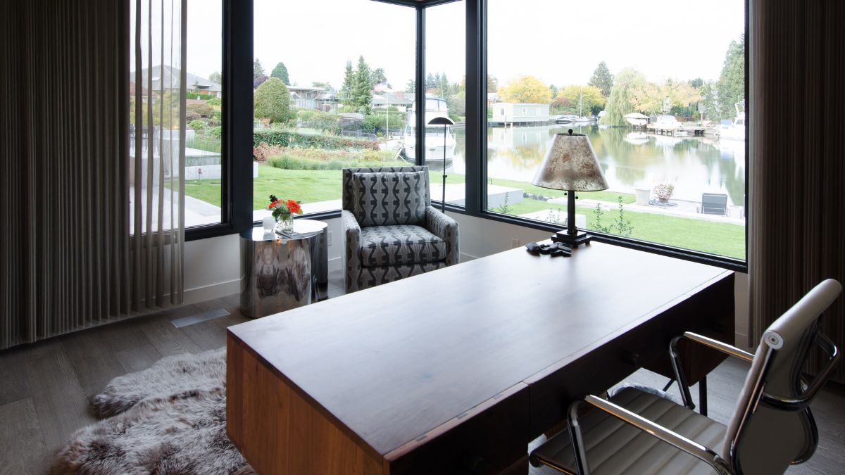 A home office in a favorable location with a glass wall that allows for outdoor views.