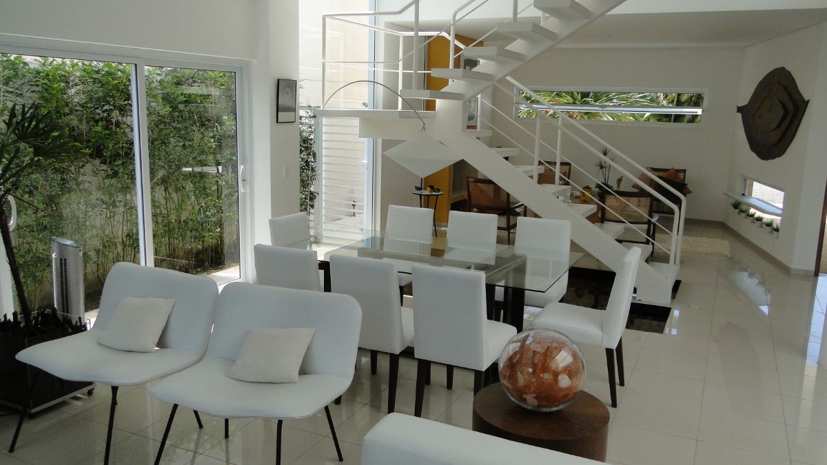 The dining area features a glass table next to the staircases.