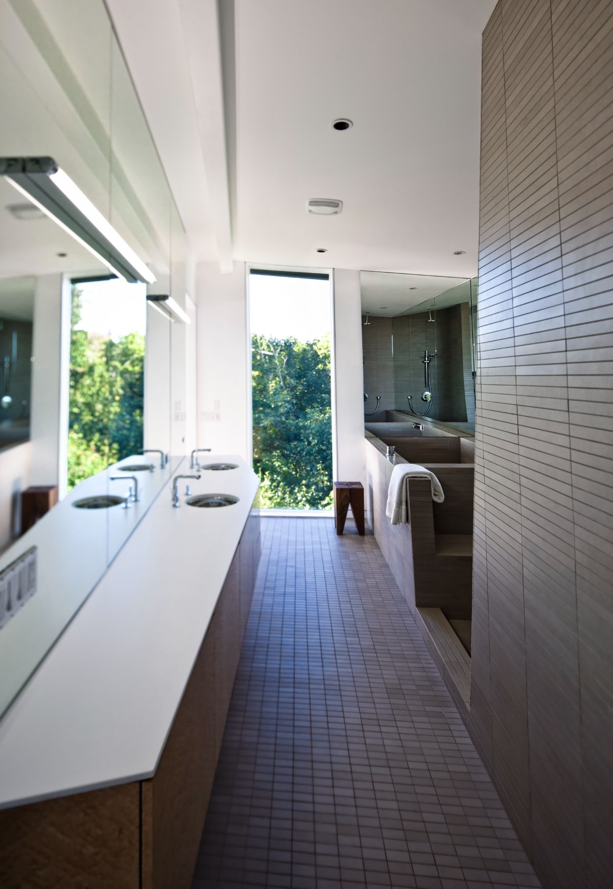 The bathroom features a vanity with a tile countertop and glass walls to let the light in the day.