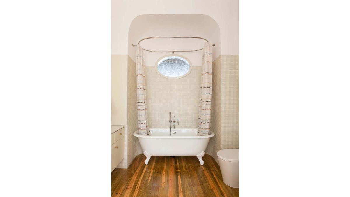 The bathroom includes a wooden floor, white bathtub, and beige walls.