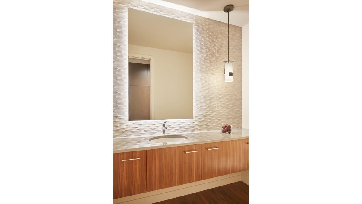 The bathroom's floors and walls are both nicely crafted, and the mirror features intriguing lights.