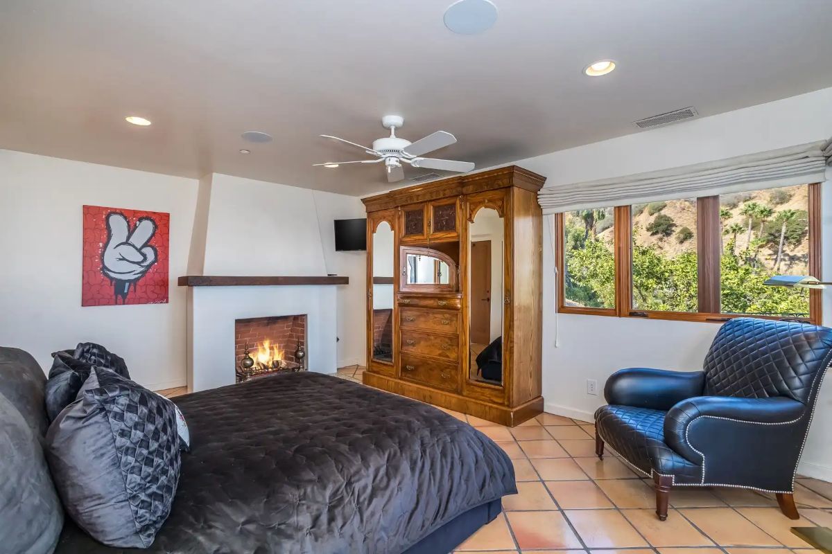 The bedroom features a fireplace and a wooden cabinet that gives the room a rustic feel.