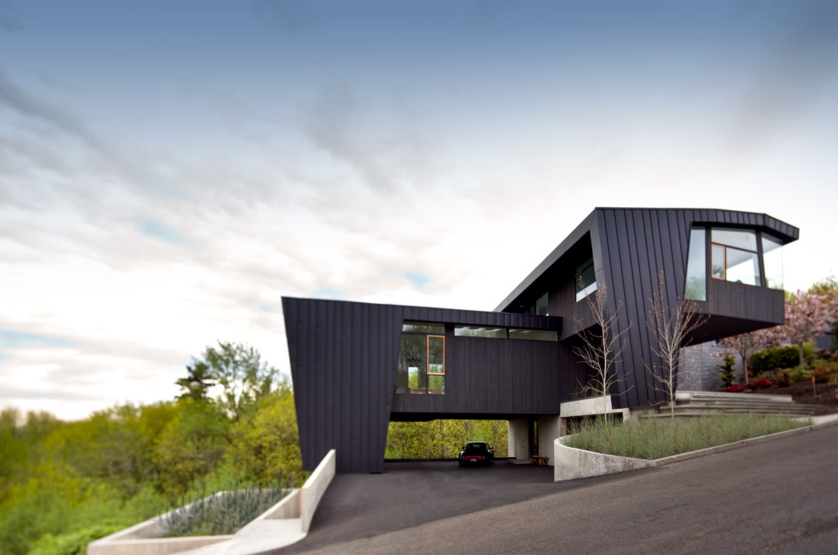 The house is situated on a slope and a cast-in-place concrete plinth was placed on the hillside creating a flat datum for garage access and carport.