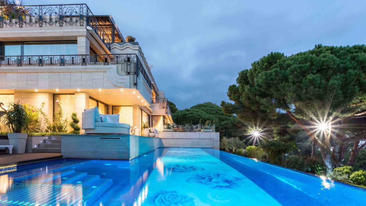 This exterior shot highlights the beautiful blue water of the pool, as well as the pleasant lighting that illuminates certain sections of the house.