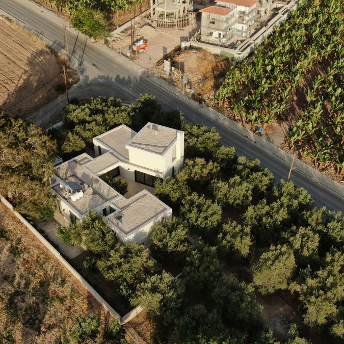 This is an aerial view capturing the residence amidst a dense canopy of trees, providing a comprehensive overview of the surrounding environment.