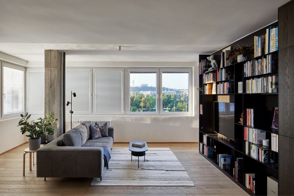 This is an interior shot of the living area, showcasing minimalist design with a wall-mounted shelving system, a sleek sofa set, and a picturesque